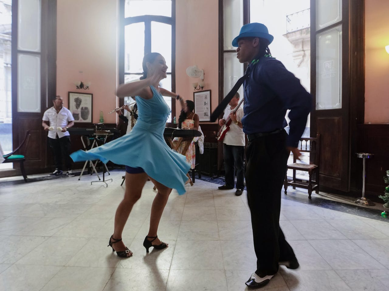 A lively couple dancing indoors with a live band in an elegant setting, exuding vibrancy and joy.